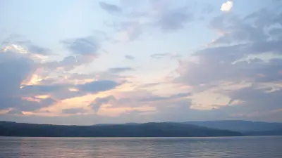 Sunset over Embden Pond and its forested shoreline.