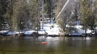 USGS streamflow measurement equipment above Grand Lake Stream beside a snowy forested bank.