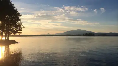 Sunset over Millinocket Lake with forested islands and Katahdin silhouetted beyond.