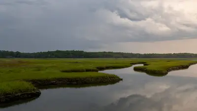 Mousam River saltmarsh channels at Parsons Beach in Kennebunk beneath a cloudy sky.