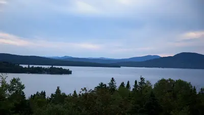 Elevated view across Rangeley Lake, wooded points and rounded mountain ridge beyond.