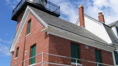 Brick and white wood exterior of Rockland Breakwater Lighthouse beneath its black lantern.